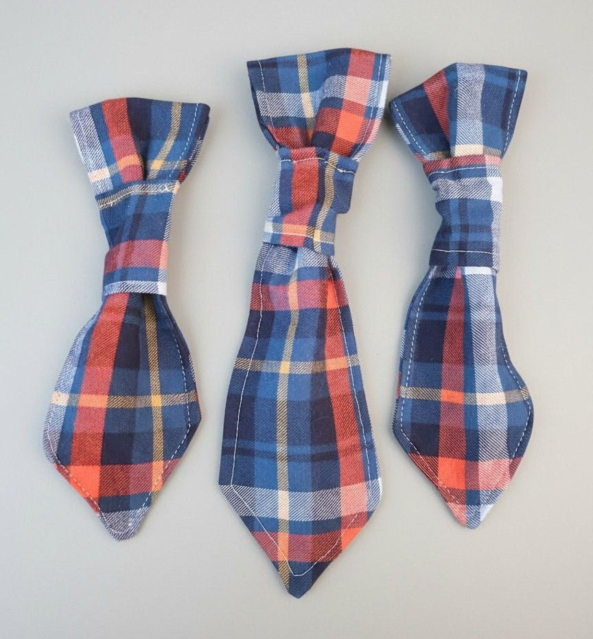 Three plaid dog ties on a light gray background